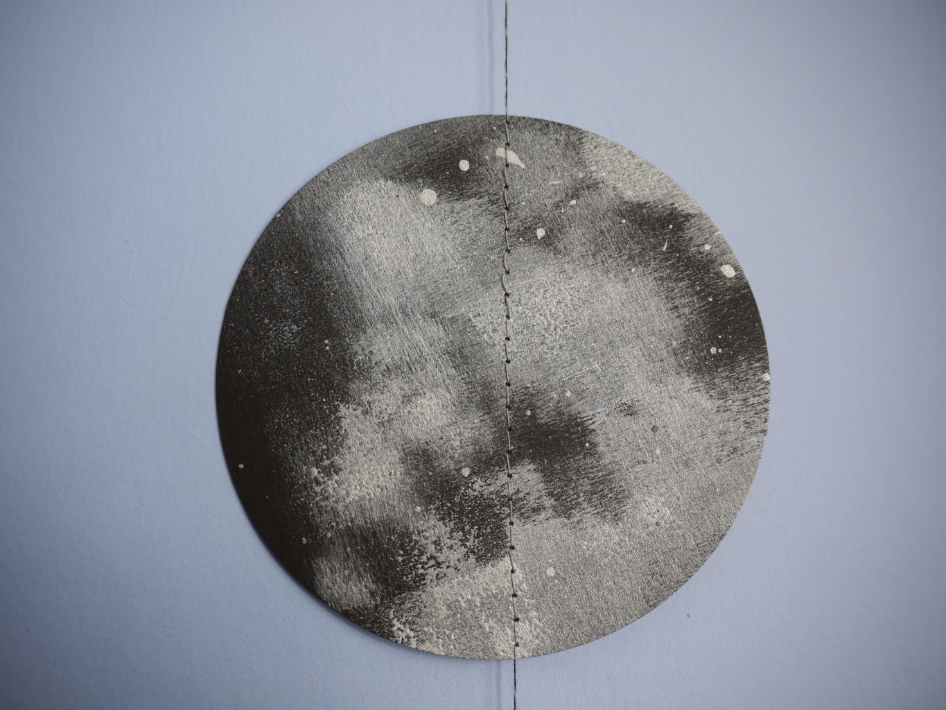 Circular metallic object with textured surface on a gray background. The full moon of a decorative wall hanging with moon phases. 