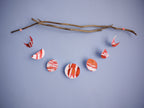Red and white moon phases garland hung horizontally from driftwood on a blue background