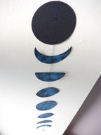 Decorative hanging with blue and black moon phases on a white background