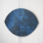 Blue painted details on a black moon phase shape, part of a moon phases wall hanging.