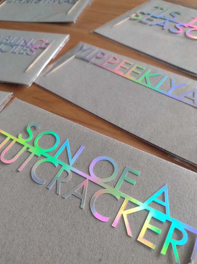 Holographic text on gray paper with 'Son of a Nutcracker' visible
