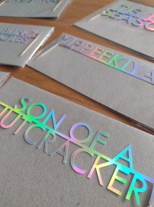 Holographic text on gray paper with 'Son of a Nutcracker' visible