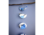 Moon phase shapes painted with blue and black ink stitched to create a wall hanging displayed on a blue background 