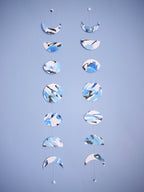 Two moon phase stitched garlands hanging vertically on a wall each painted slightly differently with blue and black ink displayed on a blue background 