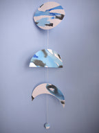 Close up of moon phase wall garland painted with blue and black ink hanging on blue wall