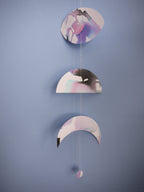 Moon phases stitched paper wall hanging garland painted with black blue and purple inks hanging  on a blue wall