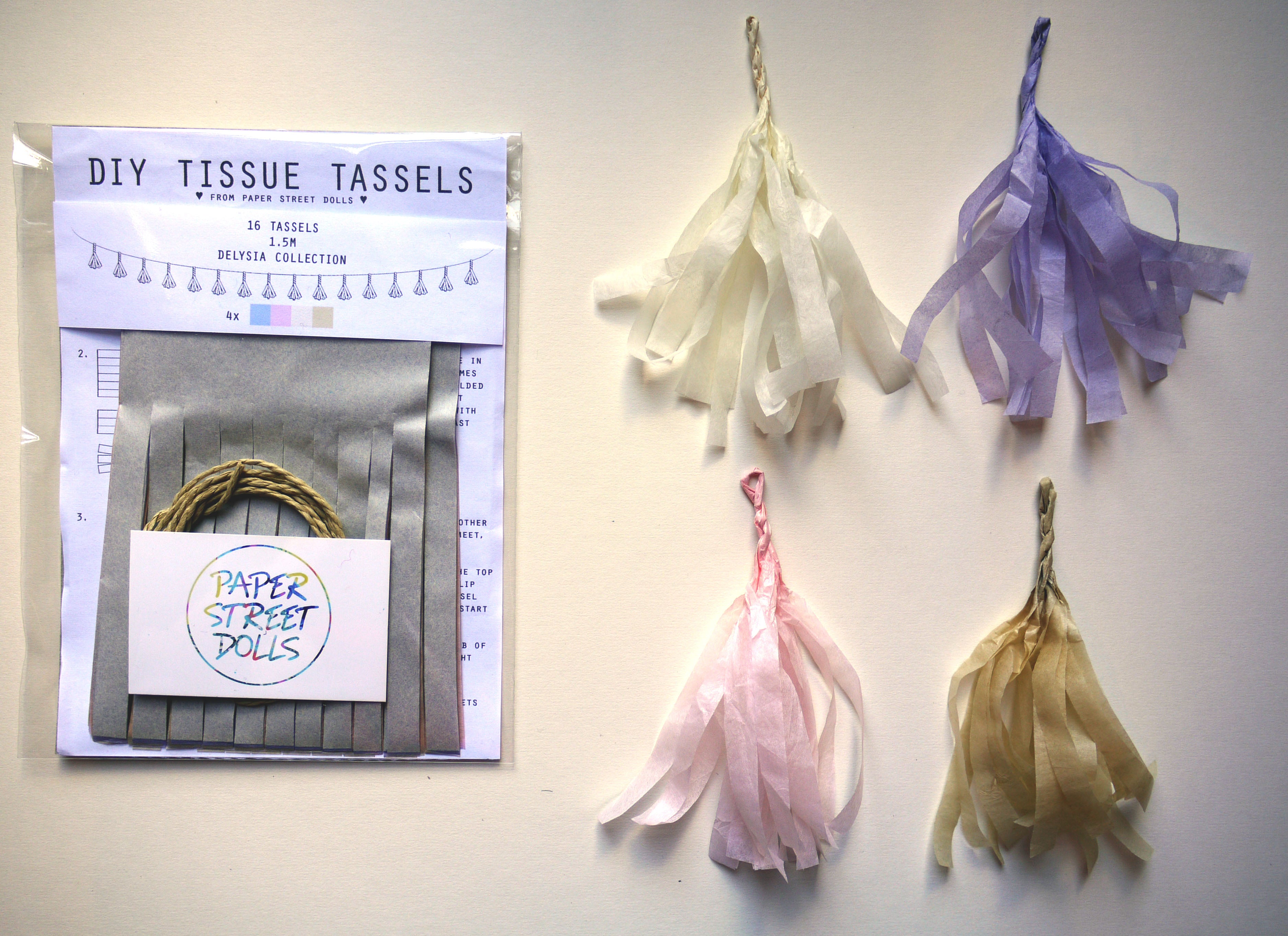 Packaging of DIY tissue tassels with colorful tassels hanging on a white background