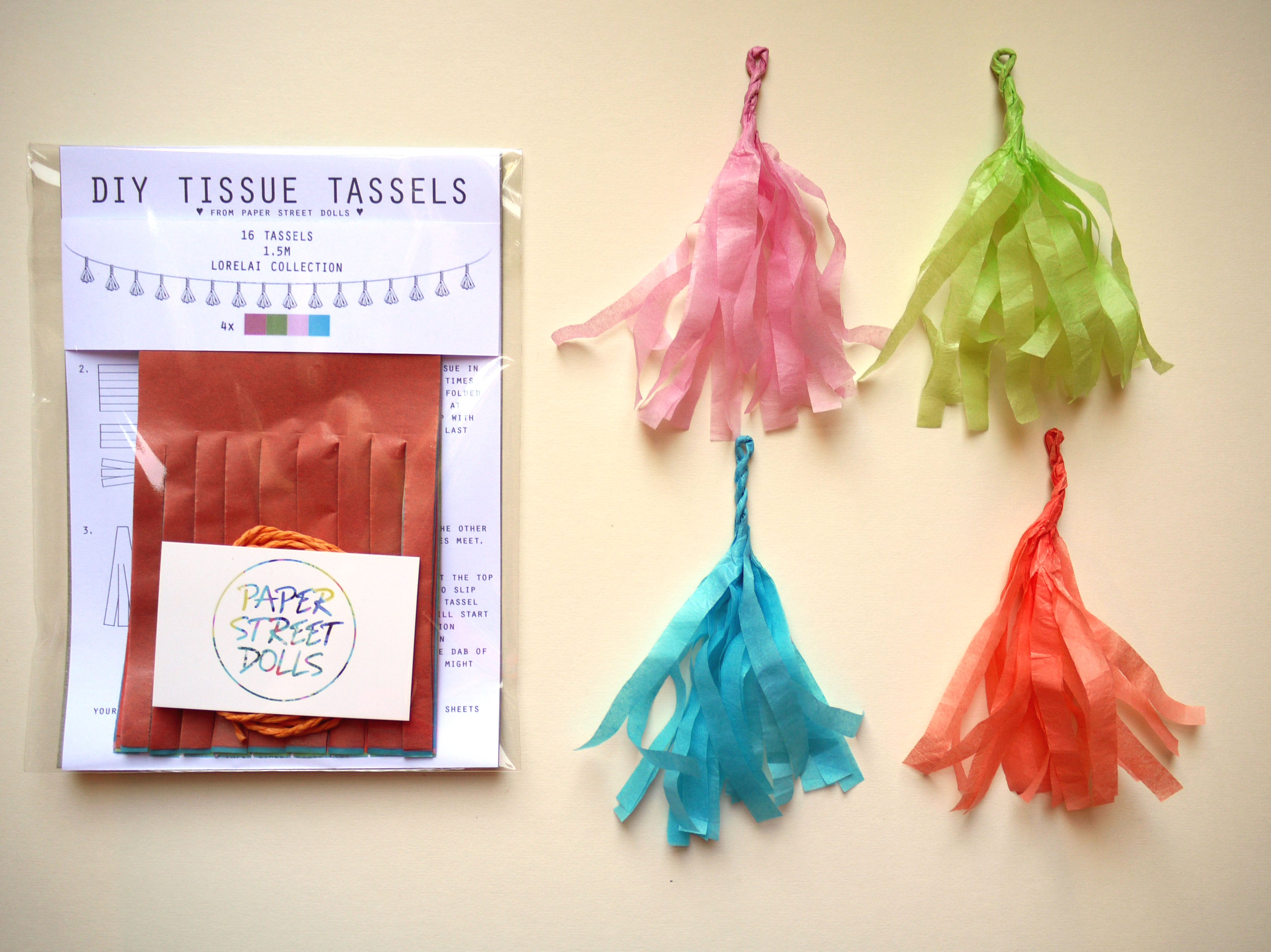 Colorful tissue tassels with a craft kit on a beige background