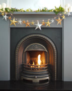 Decorative star garland above a lit fireplace with greenery.