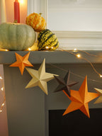 Decorative stars on a mantelpiece with pumpkins and candles