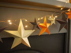 Decorative string lights with star-shaped paper garland on a dark background