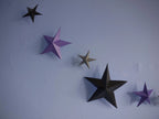 Whimsigoth DIY Samhain decorations. DIY paper star garland of 3D stars in black, purple, and pewter paper hanging against a light blue wall.