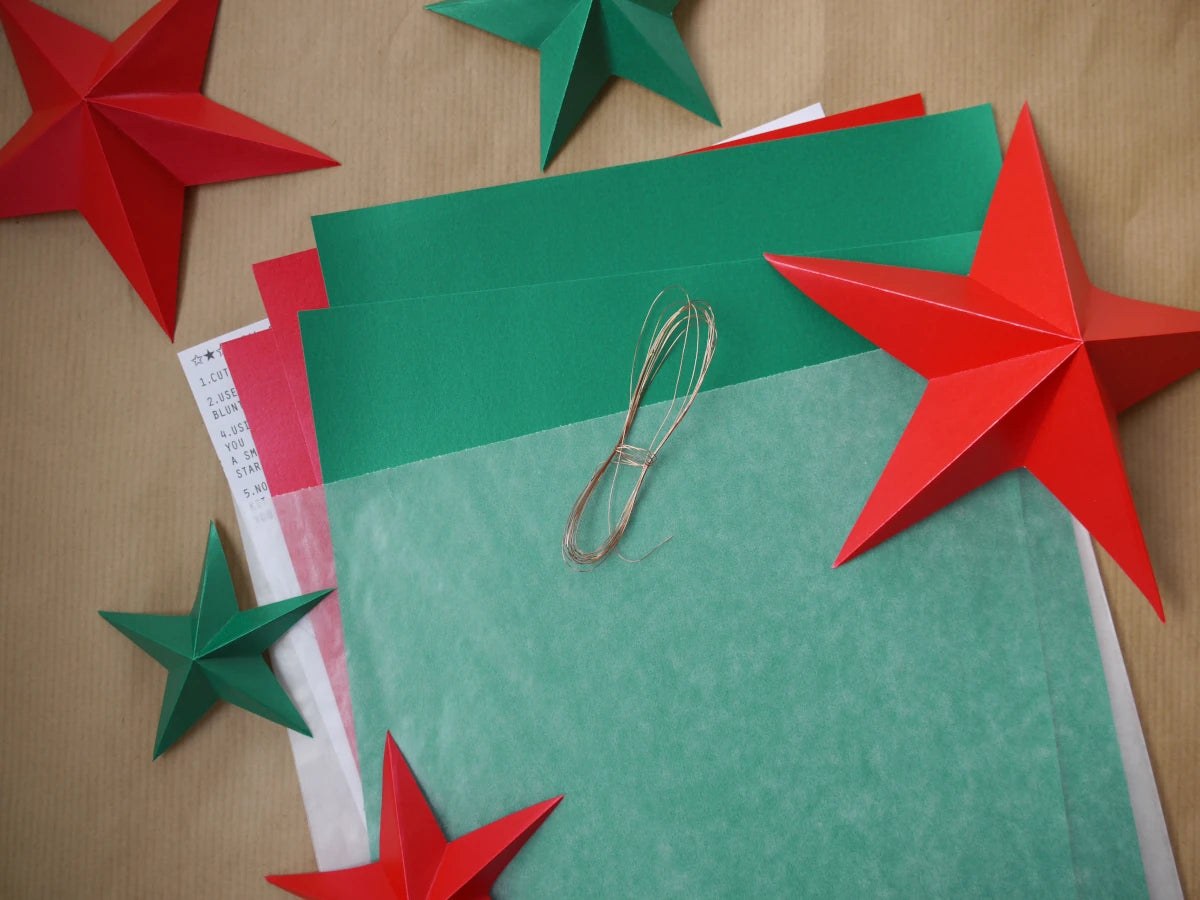 DIY paper star making for Christmas. A flat lay of layered green and red paper sheets for making paper star ornaments.