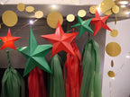 DIY paper star making for Christmas. Christmas holiday garland decoration featuring red and green paper star garland and matching red and green paper tassels, with gold circular stitched paper garland and warm string lights.