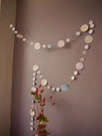 Watercolour painted paper garland in soft pastel tones on a wall, dried flowers in the foreground