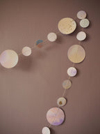 Close up on circles of watercolour painted paper garland in soft pastel tones on a wall