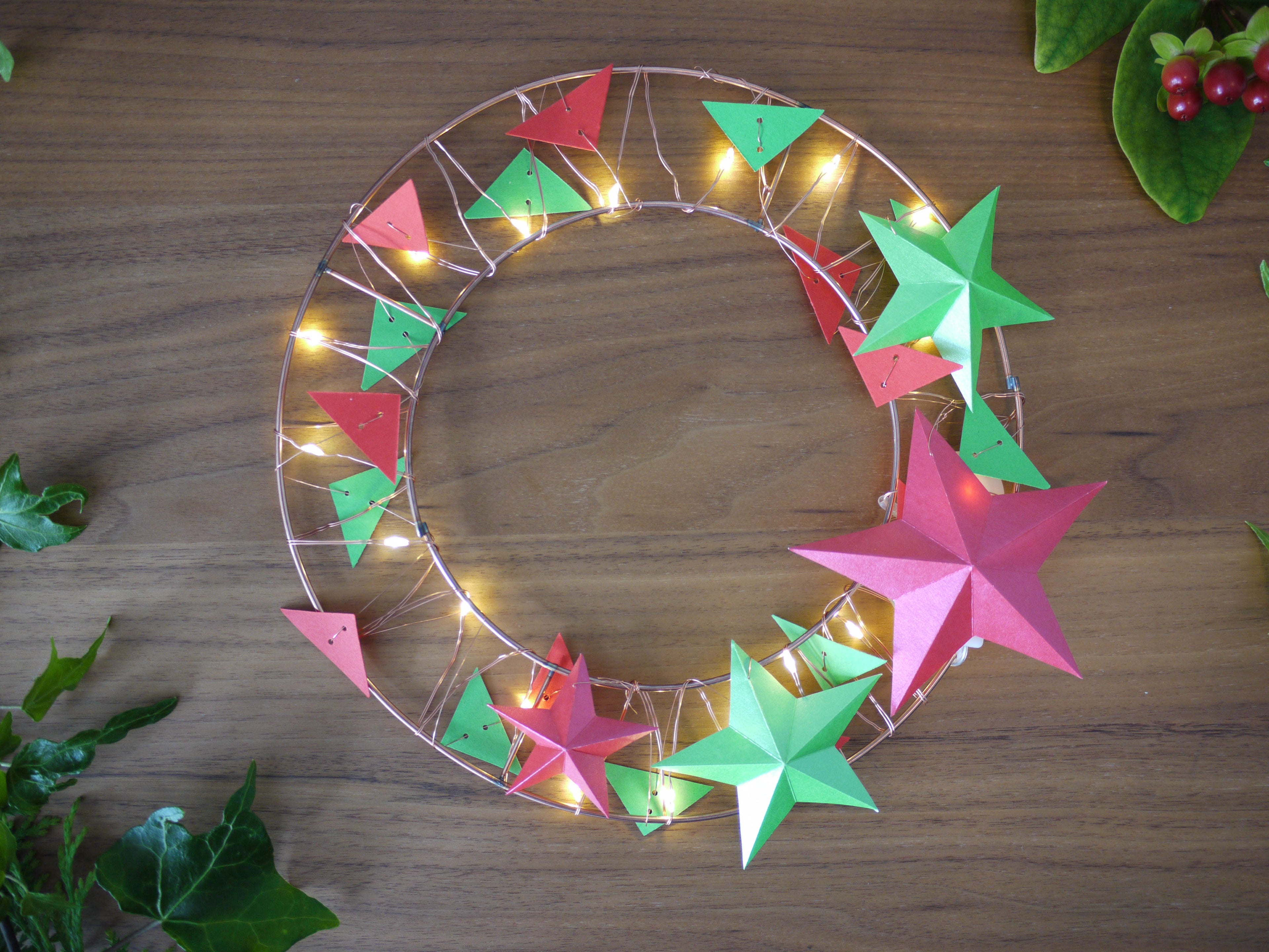 Decorative wreath with colorful star-shaped lights on a wooden surface