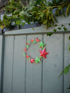 Decorative wreath with red and green stars on a wooden door
