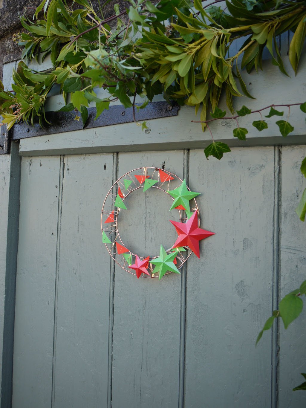 Decorative wreath with red and green stars on a wooden door