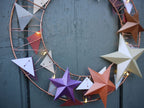 Decorative wreath with colorful star-shaped ornaments on a green wooden door.