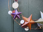Decorative wall hanging with star-shaped ornaments on a textured green wall.