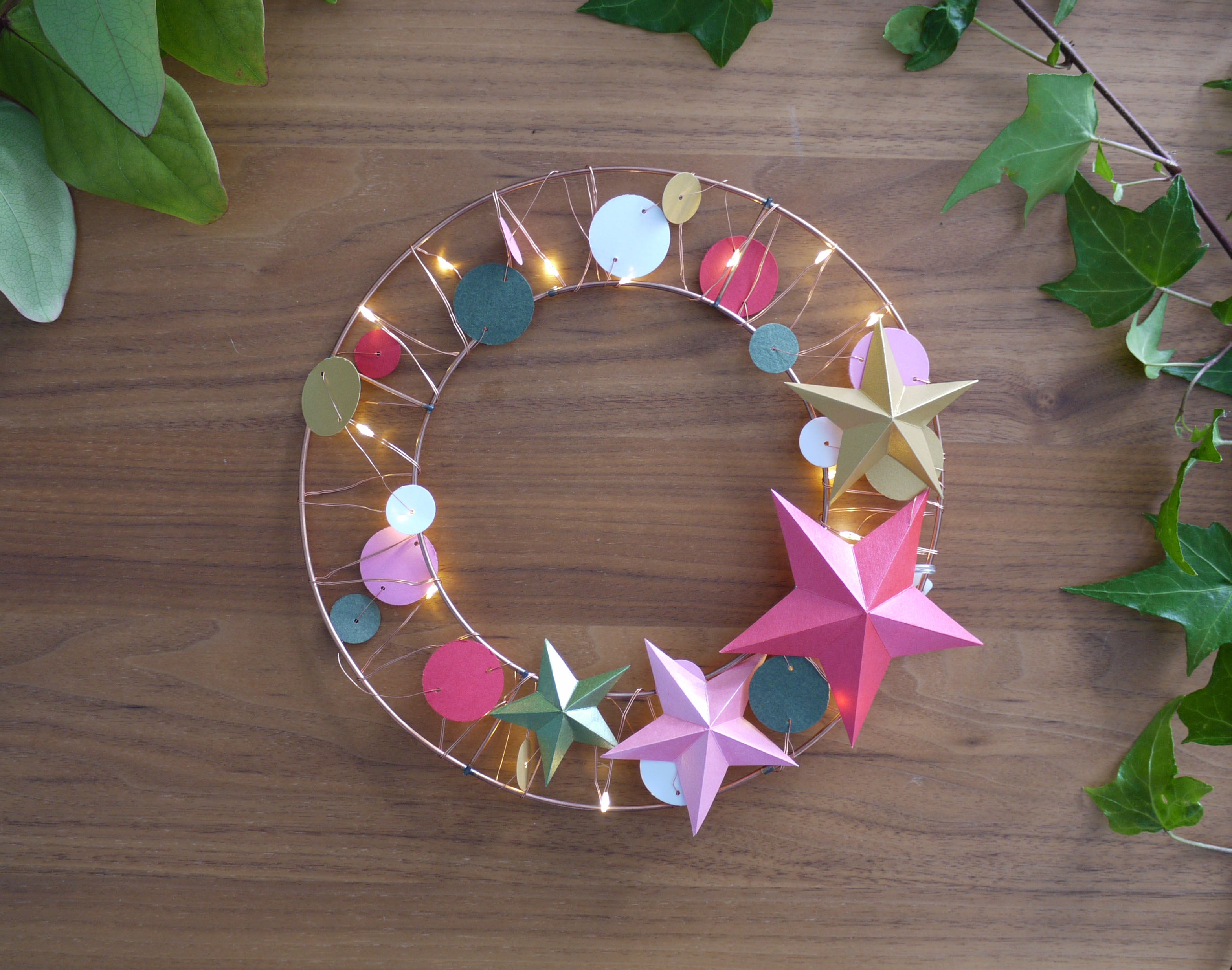 Decorative wreath with colorful stars and lights on a wooden surface