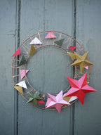 Decorative wreath with colorful paper stars on a wooden door