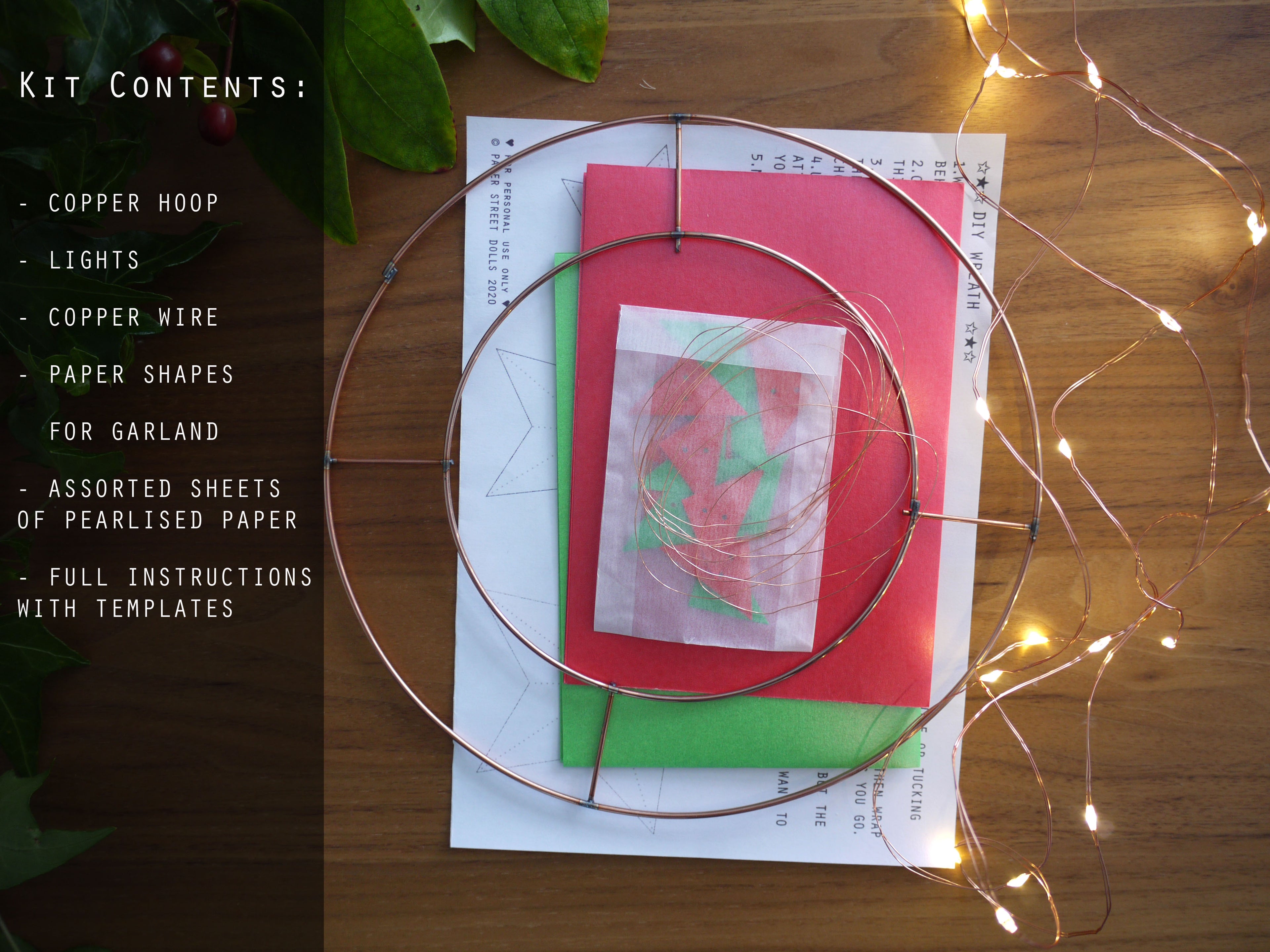Copper hoop kit with lights, paper shapes, and instructions on a wooden surface.