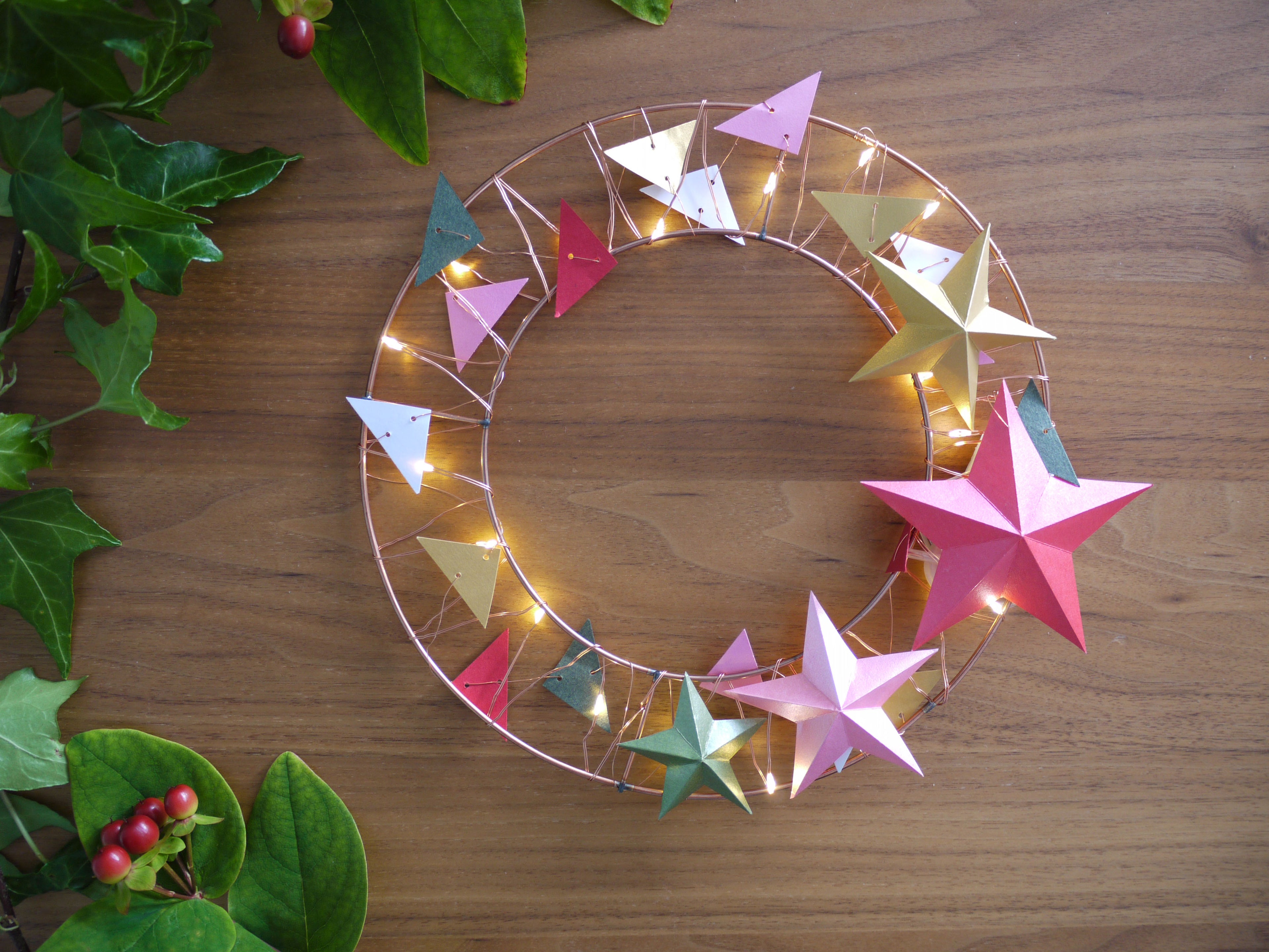 Decorative wreath with colorful star-shaped lights on a wooden surface