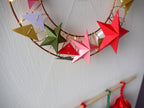Decorative wreath with colorful paper stars on a plain wall.