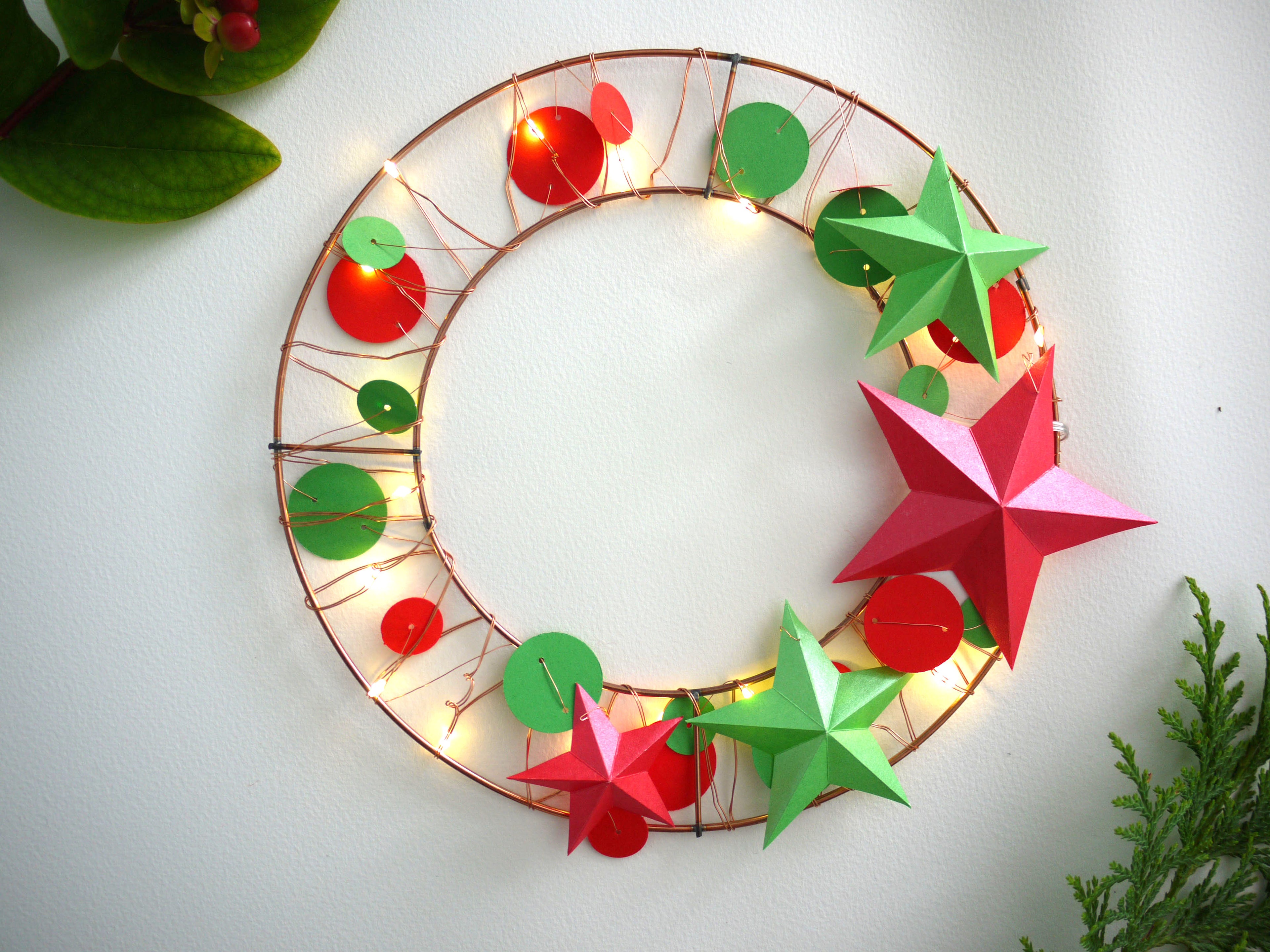 Decorative wreath with red and green stars and lights on a white background