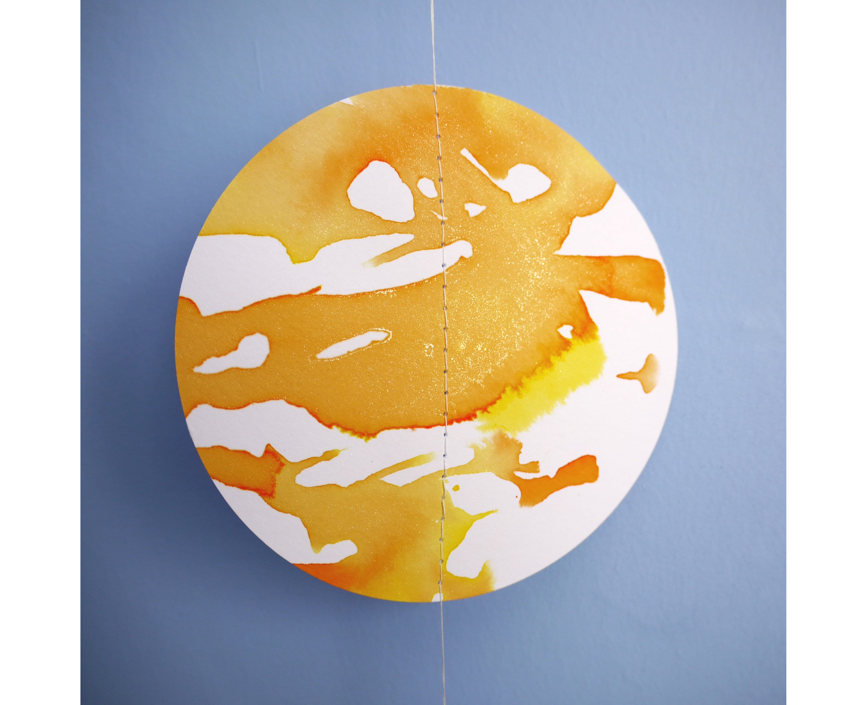 Close up on full moon of a paper garland. Hand-painted with yellow, orange and gold ink this decorative yelllow paper garland creates a full moon phases wall hanging