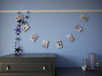 Illustrated Halloween stitched paper garland hung on a blue wall above a grey chest of drawers