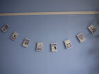 Illustrated riso printed stitched Halloween paper garland in black white and purple hanging on a blue wall