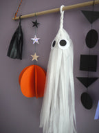 Close up on black, orange and white ghost paper decorations of the Halloween scene wall hanging