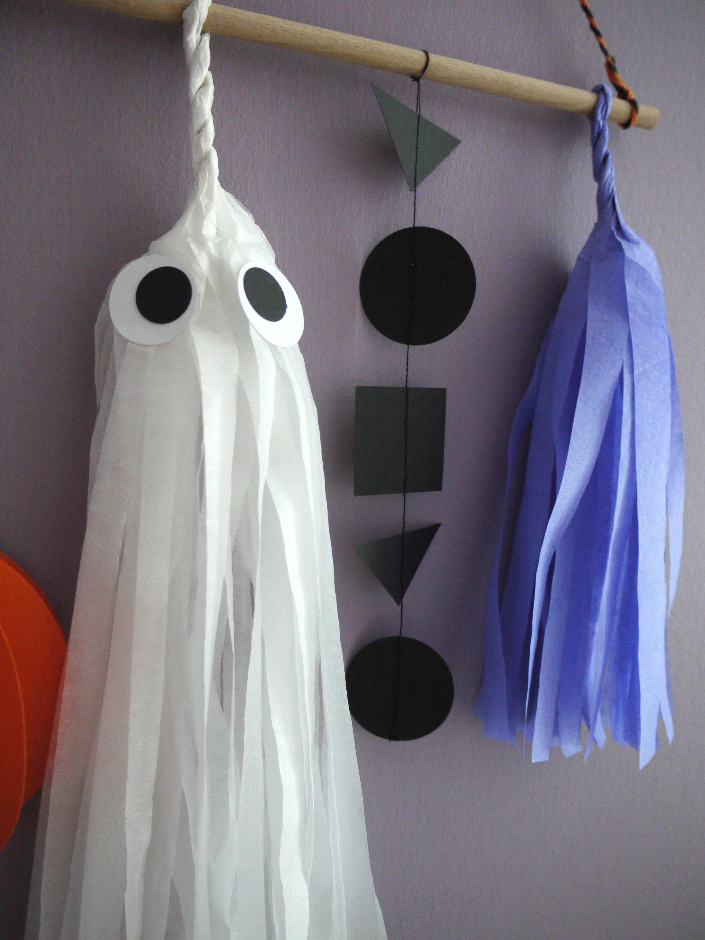 Close up on black garland, lilac tassel and white ghost paper decorations of the Halloween scene wall hanging