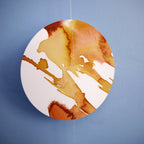 Close up of full moon shape stitched garland painted with golden tan and brown inks displayed as a wall hanging on a blue background 