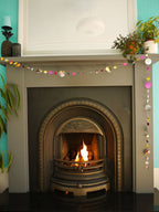 Painted paper garland in bold colours of pink, yellow, black, purple and holographic, sitting at a fireplace