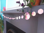 pink, yellow, orange and turquoise marbled paper garland on the mantelpiece
