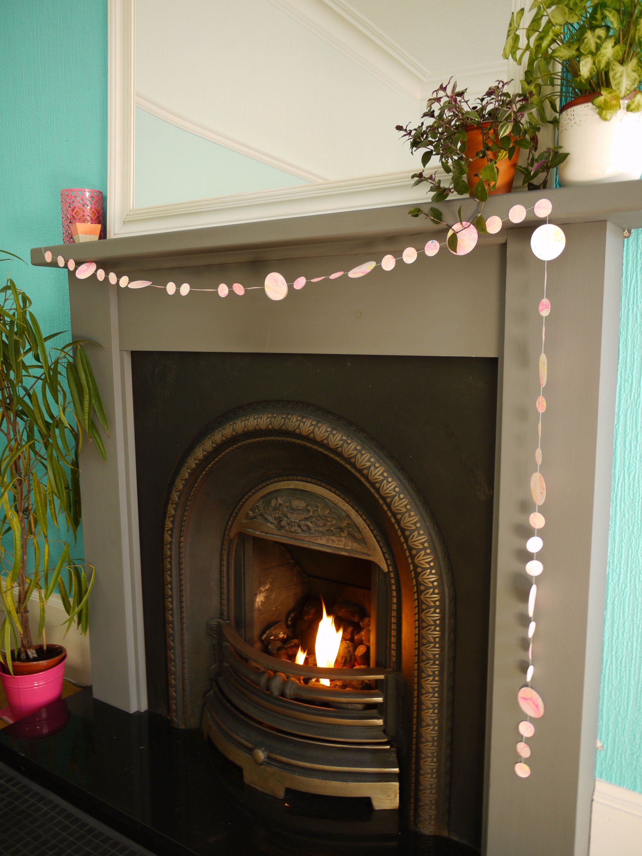 pink, yellow, orange and turquoise marbled paper garland on the mantelpiece