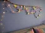Bedroom decor of pink, yellow, orange and turquoise marbled and geometric paper garlands wall display with driftwood and fairy lights