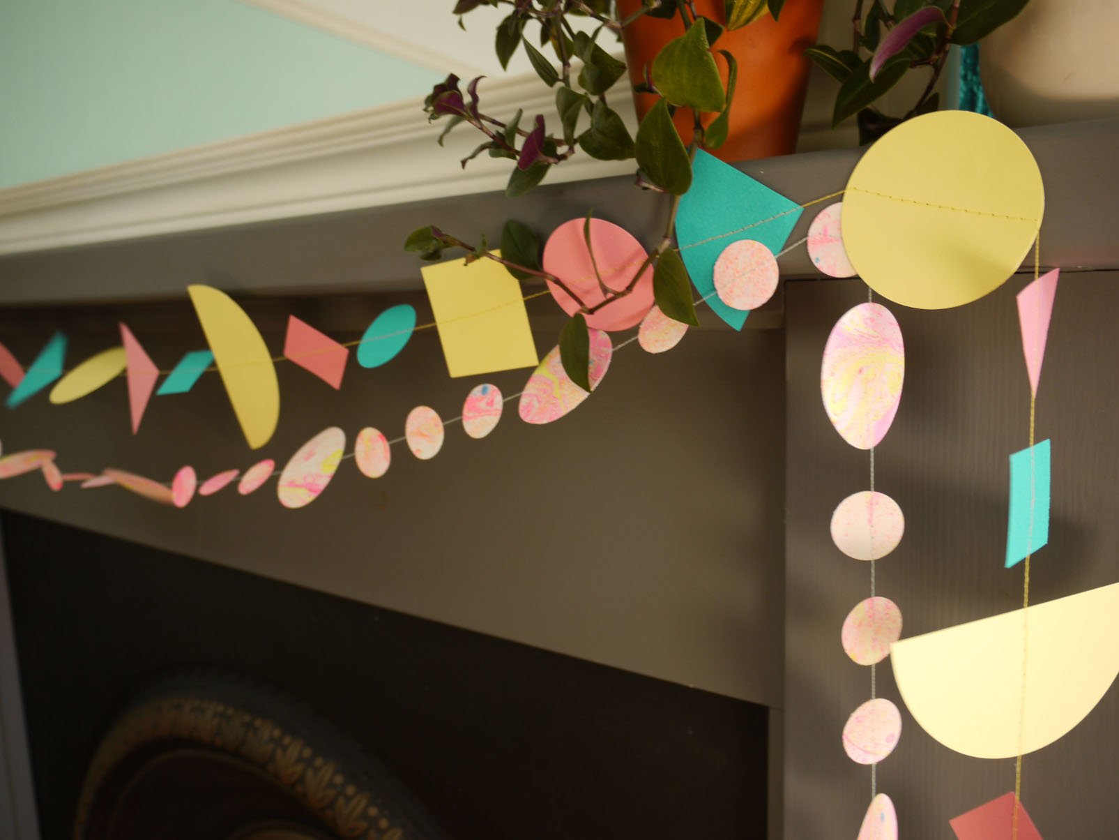 Living room fireplace display of Paper Street Doll's LORELAI geometric and marbled paper garlands in tropical colours