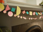 Living room fireplace display of Paper Street Doll's LORELAI geometric and marbled paper garlands in tropical colours