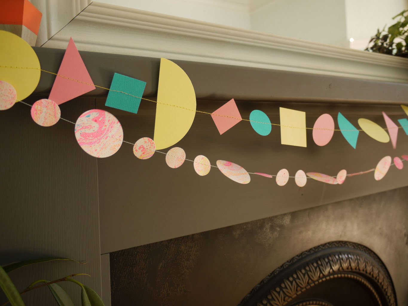 Living room fireplace display of Paper Street Doll's LORELAI geometric and marbled paper garlands in tropical colours