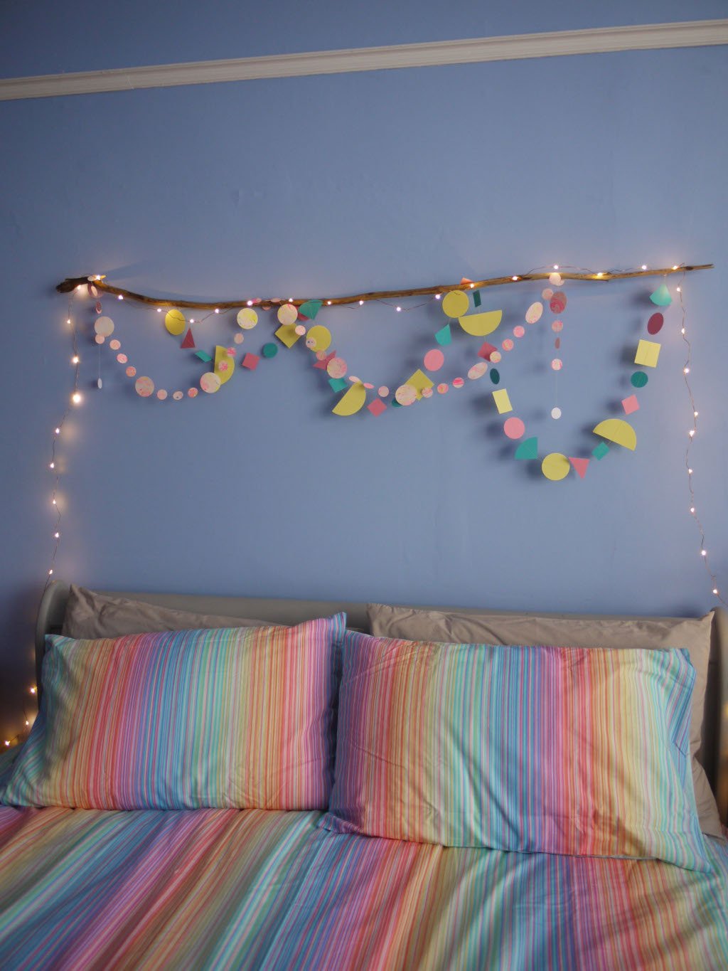 A bedroom wall hanging of Paper Street Doll's LORELAI paper garlands  with driftwood and fairy lights