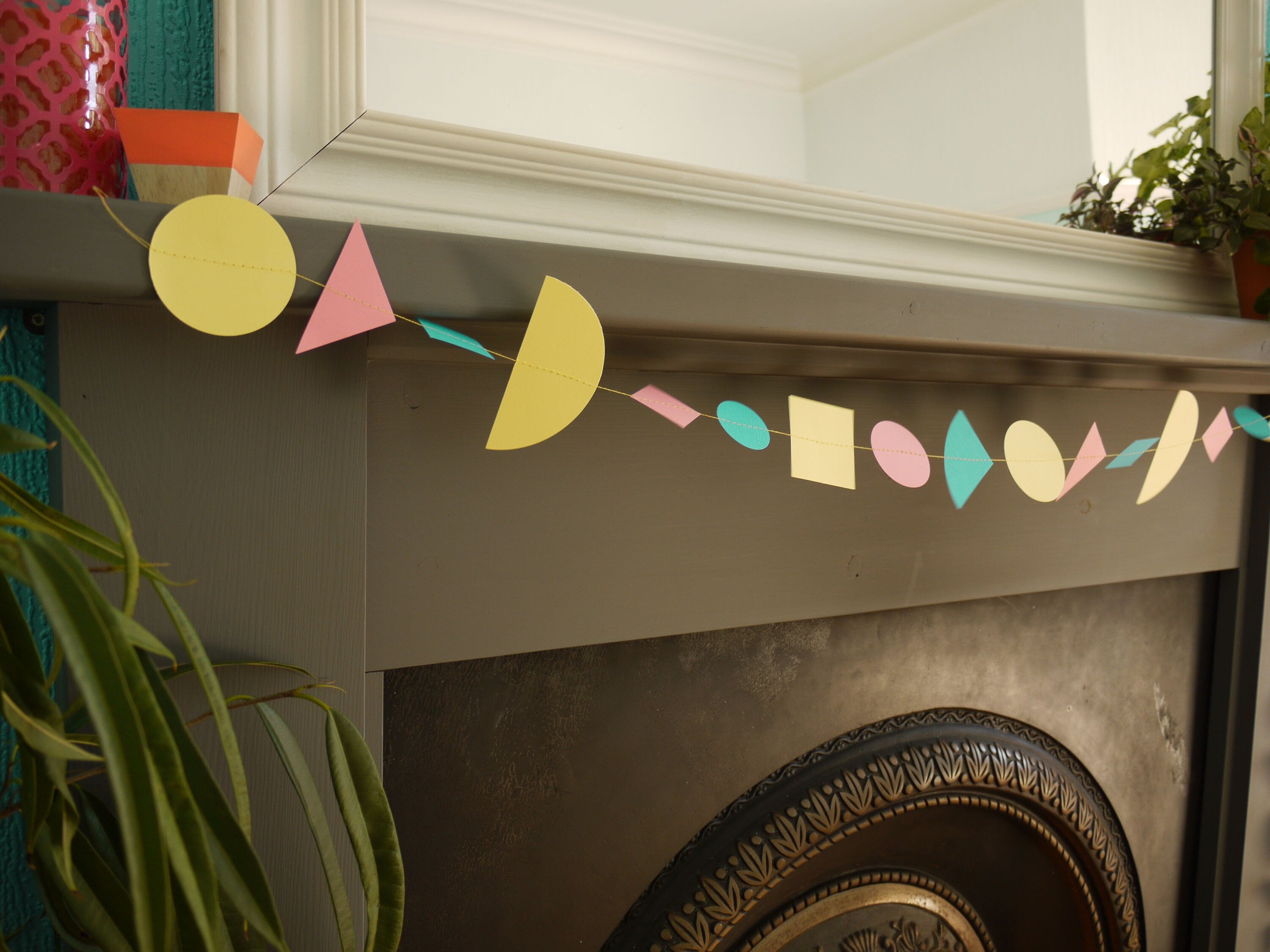 Mantelpiece display with modern multi shape paper garland in Paper Street Doll's LORELAI colours of aqua, lemon yellow and rose