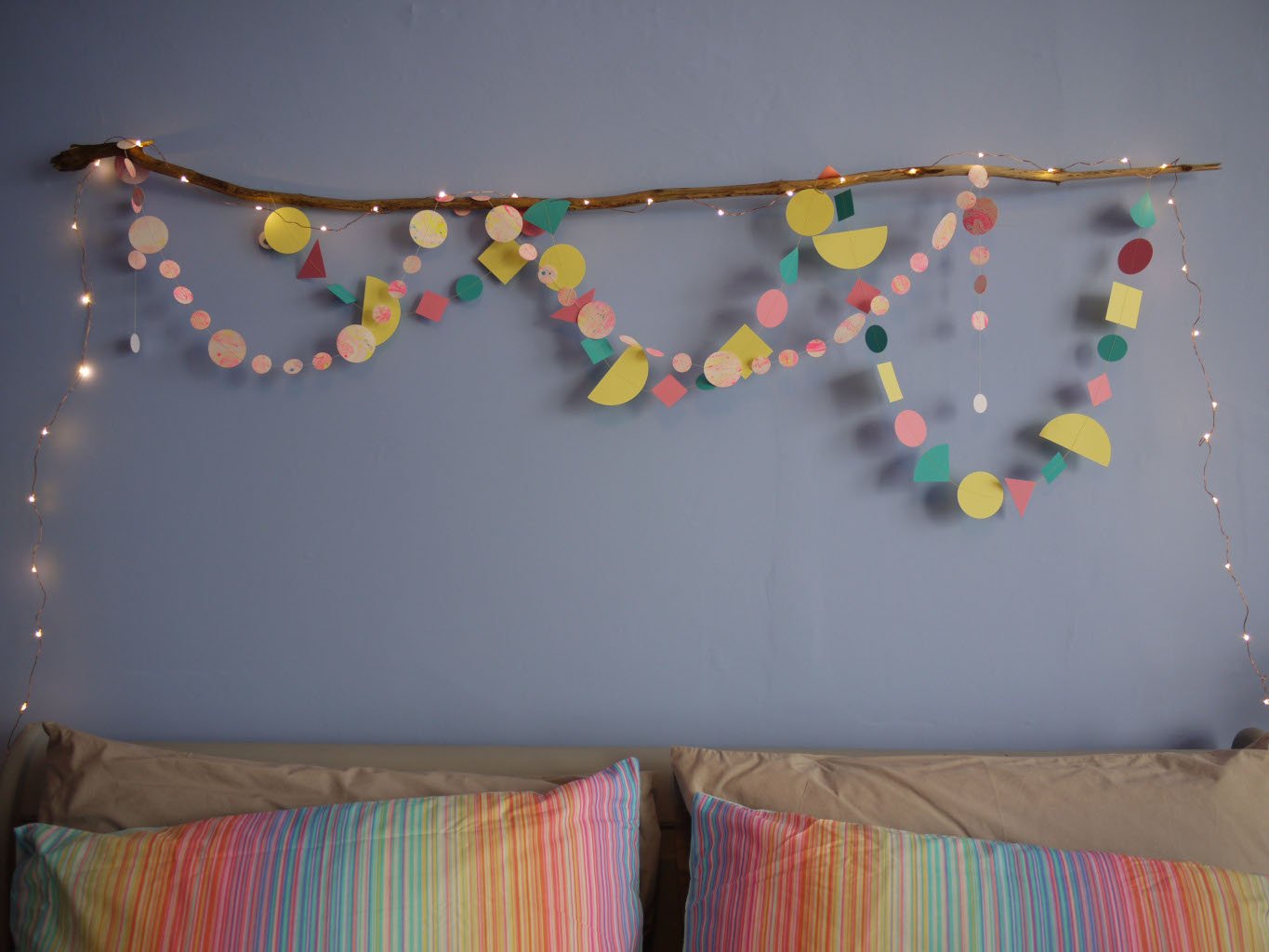 A bedroom wall hanging of Paper Street Doll's LORELAI paper garlands  with driftwood and fairy lights