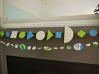 Geometric and watercolour paper garlands in Paper Street Doll's OPHELIA colours of grey, grass green and blue at a fireplace