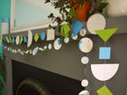 Geometric and watercolour paper garlands in Paper Street Doll's OPHELIA colours of grey, grass green and blue at a mantelpiece
