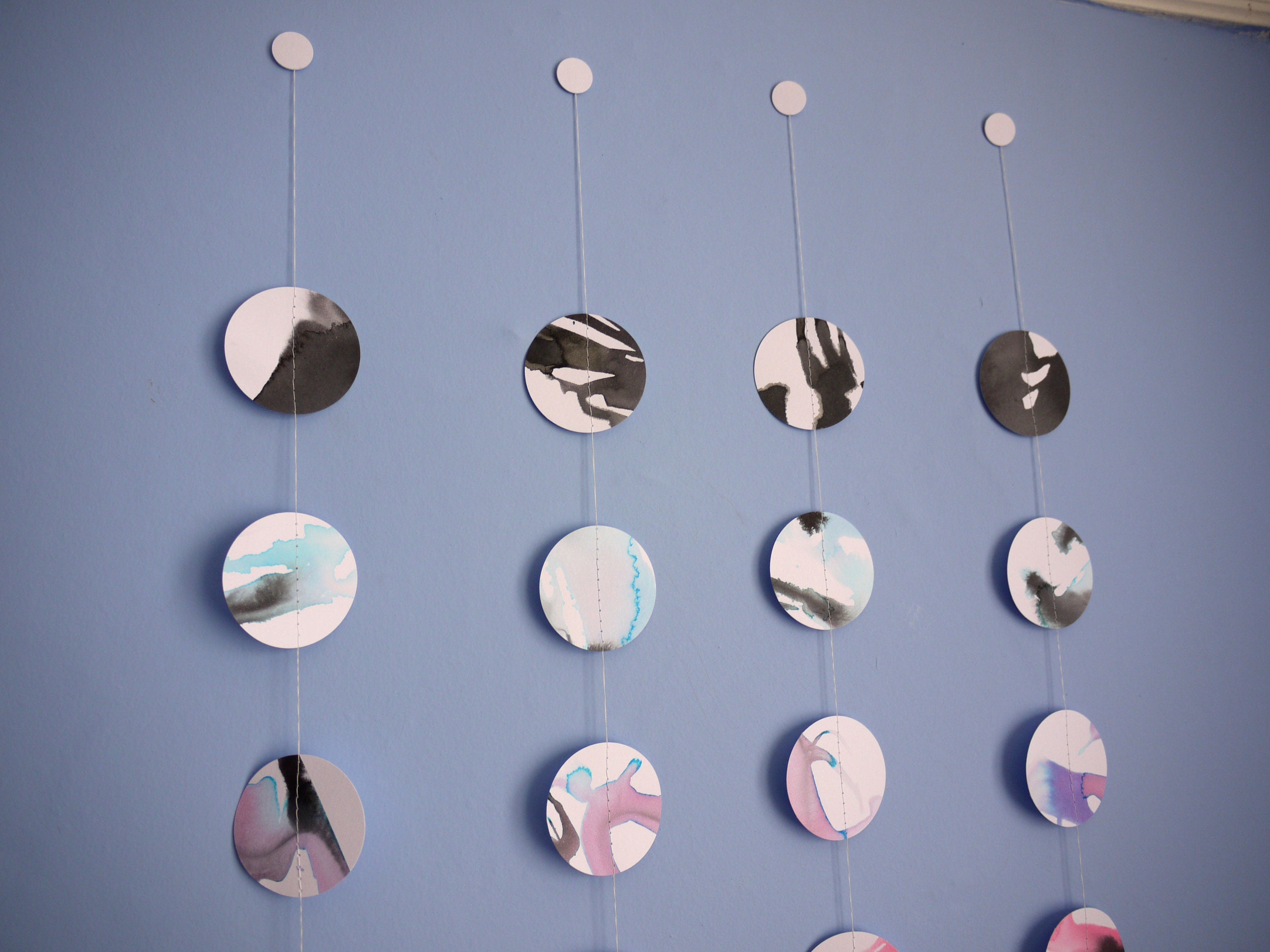 Close up on the top of four multicolour full moon paper garlands showing the unique look of each 